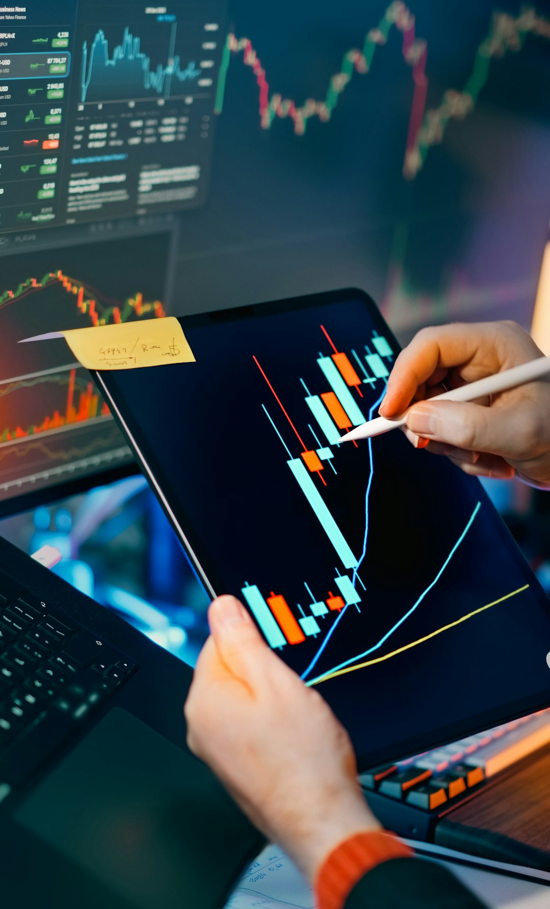 Stock crypto trading analysis workstation. Closeup hands stylus tablet touchscreen candlestick charts indicators price movement market volatility investing savings portfolio strategy risk management finance technology screens dashboard night lighting focus performance growth profit data economy currency blockchain laptop monitor